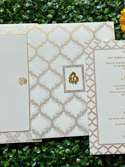 An elegant white and gold invitation with a classic Moroccan tile pattern. The design is sophisticated and timeless.