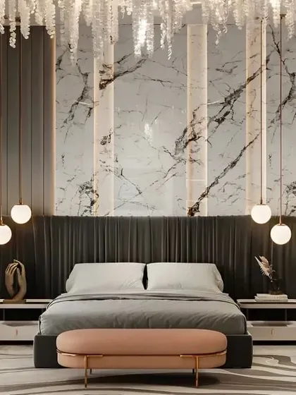 This opulent bedroom design showcases a stunning marble feature wall with integrated vertical lighting. The plush, oversized headboard and cascading crystal chandelier add to the room's grandeur and luxurious feel.