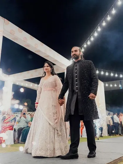 The couple's grand entrance at their reception. The pathway is lined with sparklers, creating a dramatic and celebratory welcome as they walk hand-in-hand.