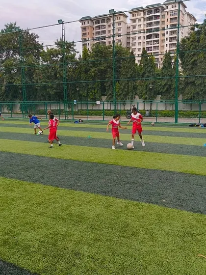A group of young players in red uniforms practice their dribbling skills in a coordinated drill.