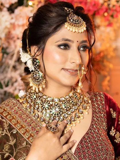 A side profile of the bride, showcasing her elegant hair and the details of her nose ring and earrings.