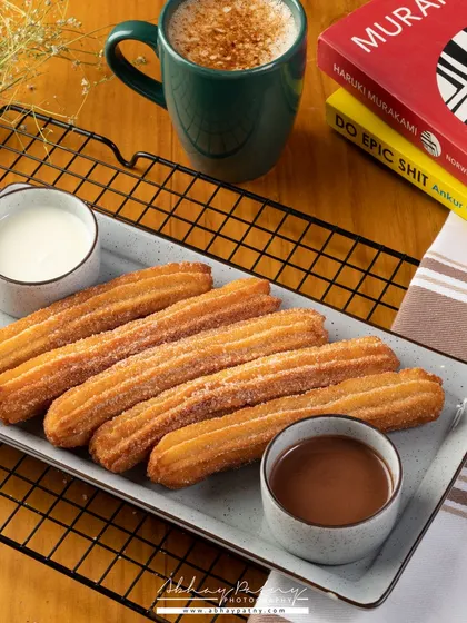 Churros are all about the texture and the delicious dips. I arranged them neatly on a platter with coffee to create a perfect "coffee and dessert" scene for a cafe menu.