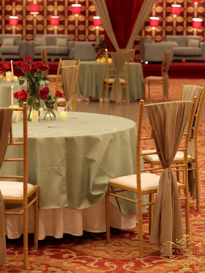 Guest seating for the after-party, with sage green tablecloths and elegantly draped chairs, set against the vibrant red lounge area.