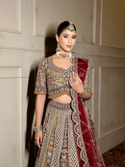 A front-facing portrait of the bride, her hands gently holding her dupatta.
