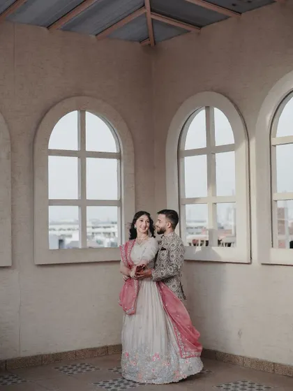 A wide shot of the couple framed by beautiful arched windows, creating a sense of grandeur and architectural beauty in their engagement photos.
