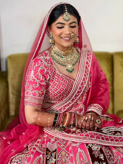 This bride's smile lights up the room. Her hair is styled in a classic bun, allowing her beautiful jewelry and outfit to shine.