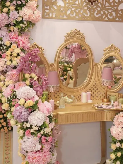 A golden vanity table surrounded by lush floral arrangements, part of the regal bachelorette party decor.