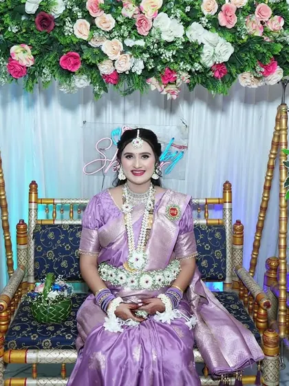The mom-to-be seated on the decorated swing, looking radiant in her full set of custom floral jewellery.