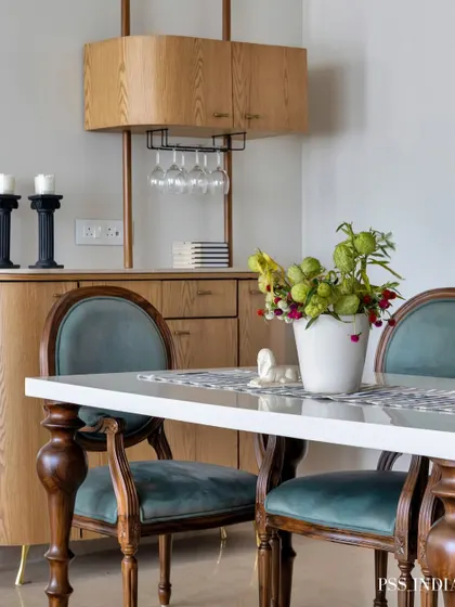 This dining area features a sophisticated bar cabinet, perfect for entertaining. The classic wooden chairs with teal velvet upholstery add a touch of vintage glamour, while the modern bar unit provides practical storage.