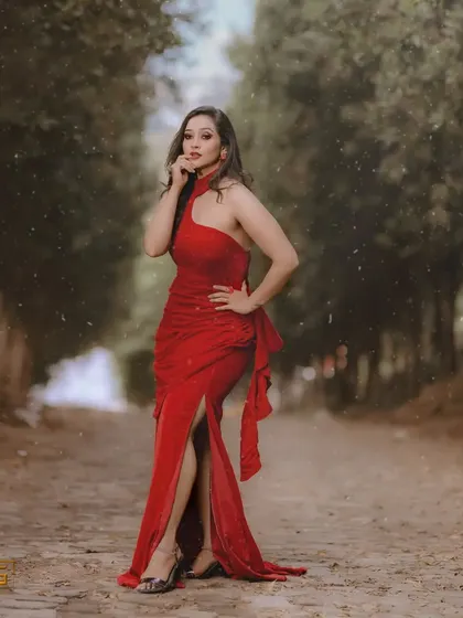 A full-length shot of the model in the red gown in a beautiful, moody outdoor setting.