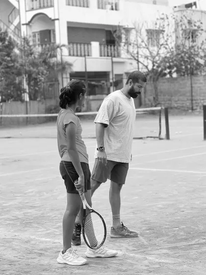 A black and white shot of me coaching a young player. This captures the essence of what we do: personalized guidance to nurture the next generation. Launching soon.