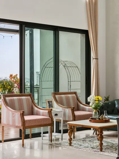 This accent chair, upholstered in muted rose tones with a warm wood frame, whispers timeless elegance. It’s a piece that blends handcrafted detail with modern comfort, perfect for a quiet corner in the living room.