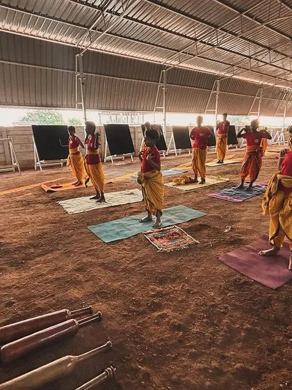 Students practice physical conditioning exercises with traditional Indian clubs (mudgars). This training builds the shoulder, back, and arm strength necessary to draw powerful bows.