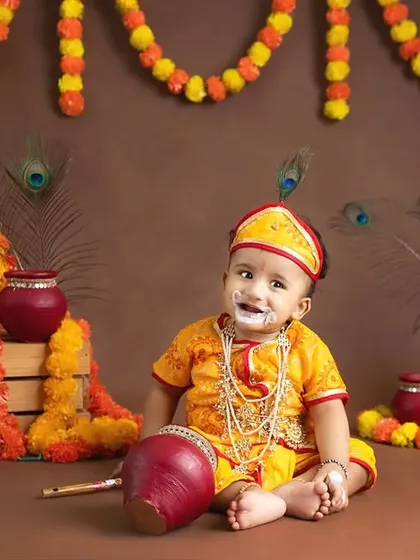 A baby as little Krishna with "butter" on his face, holding a flute prop.