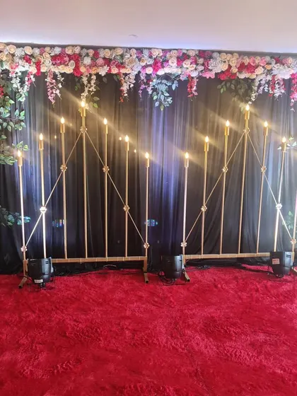This is a stylish backdrop perfect for a Mehndi or Sangeet night. The dark curtain makes the floral arrangement and the warm, candle-style lights pop, creating a dramatic and beautiful photo corner.