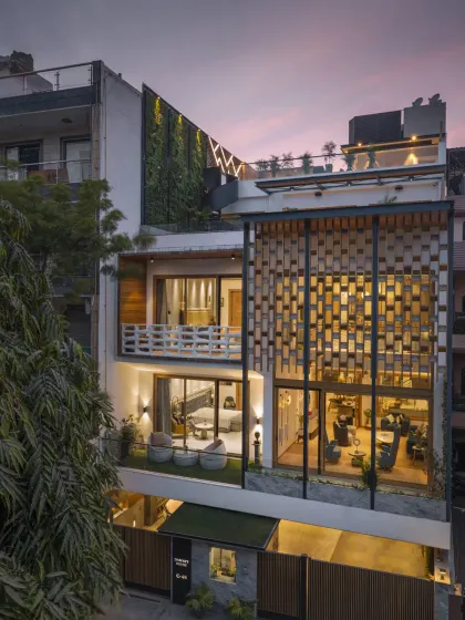 The Screen House is structured across four levels, with the stilt floor designed as an entertainment hub. This evening view shows the seamless blend of leisure spaces with the home's primary residential functions, all visible through the open façade.