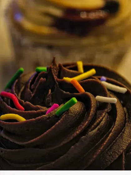 An extreme close-up of a chocolate cupcake, focusing on the rich swirls of frosting and colorful sprinkles. This macro shot emphasizes texture and detail, making the dessert look incredibly tempting.