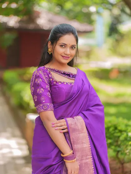 A smiling portrait of the model, giving a clear view of the front of the embroidered purple blouse.
