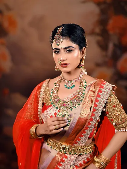 A classic pose that highlights the intricate details of the bridal jewellery and the rich embroidery on the blouse. The floral background adds a touch of softness.