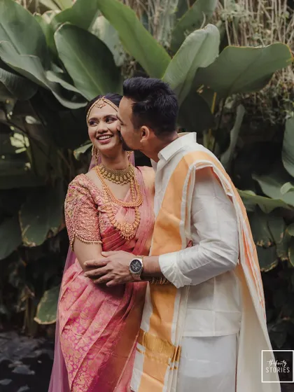 A stolen moment of affection amidst the wedding festivities. The groom's gentle kiss on the bride's cheek is a perfect example of the candid, romantic photography we specialize in.