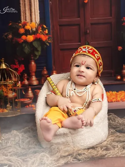 A tiny Krishna sitting in a miniature chair against a backdrop that looks like a palace courtyard. Every detail is carefully planned for these festive shoots.