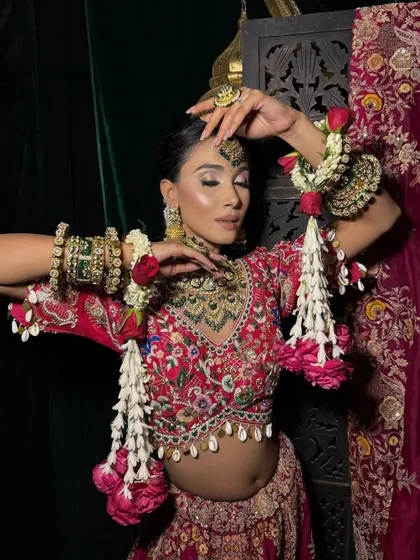 The floral kaleeras add a fresh, modern touch to this traditional bridal look. The makeup is kept timeless with a focus on glowing skin and defined eyes to complement the vibrant outfit.