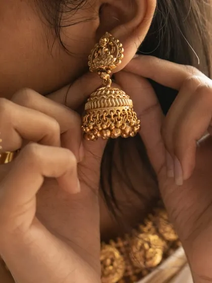 A close-up on the classic temple jhumka. This earring design is timeless and adds a touch of grace to any traditional outfit.