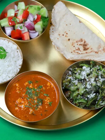 A healthy and tasty meal of paneer bhurji, stir-fried bitter gourd (karela), rice, roti, and salad. Eating your greens has never been so delicious.