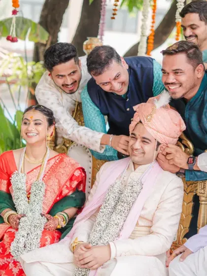 The groom's friends playfully adjust his turban during the ceremony. This candid moment shows the fun and camaraderie of the wedding day.