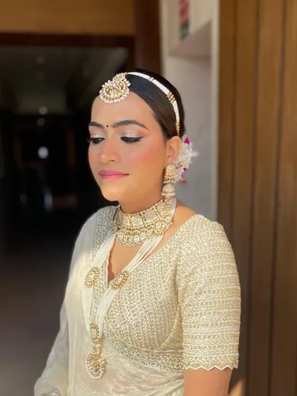 A front view of the bride with her pearl and hydrangea bun. The hairstyle is designed to beautifully accommodate her matha patti and other jewelry.