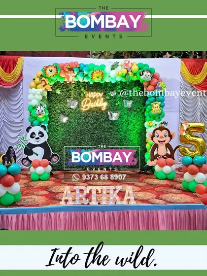 Into the wild for a 5th birthday! This jungle theme features a full balloon arch over a grass backdrop, complete with fun animal cutouts and the birthday girl's name in light-up letters.