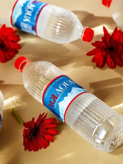 A playful pattern created with multiple Volaqua water bottles and bright red flowers. This top-down shot is visually engaging and creates a feeling of abundant refreshment.