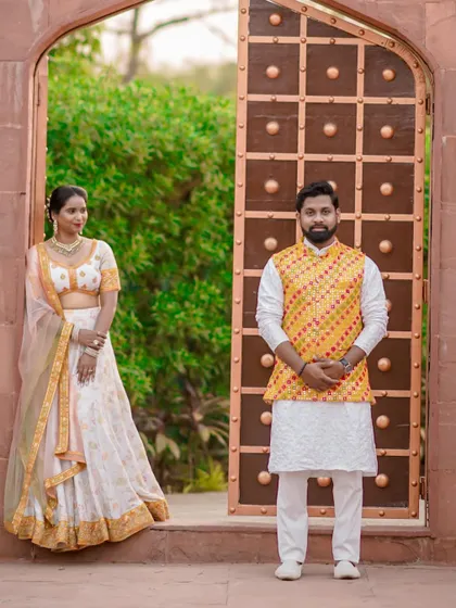 A classic portrait using the grandeur of a traditional doorway as a frame. This shot highlights the couple's elegant ethnic outfits and confident poses.