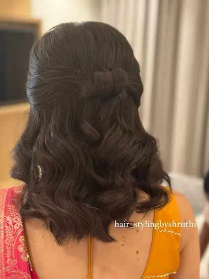 A simple and chic half-up style on shoulder-length hair, featuring a subtle hair bow created from the hair itself. This shows that beautiful styles can be created on any hair length.