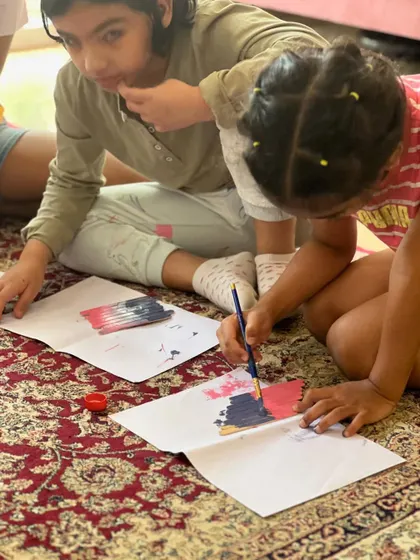 Kids working together to paint their popsicle sticks. This is the first step in creating their very own decorative wall hanging.