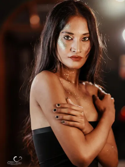 A vulnerable yet strong pose. The way she holds herself, combined with the artistic glitter makeup, tells a story of self-protection and inner light.