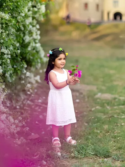 A lovely portrait of a girl with a floral headband, with a beautiful pink color flare adding a creative touch.