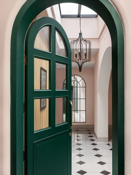 The entrance to the Quiet Ornate home makes a bold first impression. We chose a striking emerald green for the arched door, which opens into a skylit foyer with classic marble inlay floors, setting a tone of understated drama.