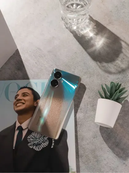 A flatlay of the realme 10 Pro+ 5G on a magazine, with dramatic lighting creating interesting shadows.