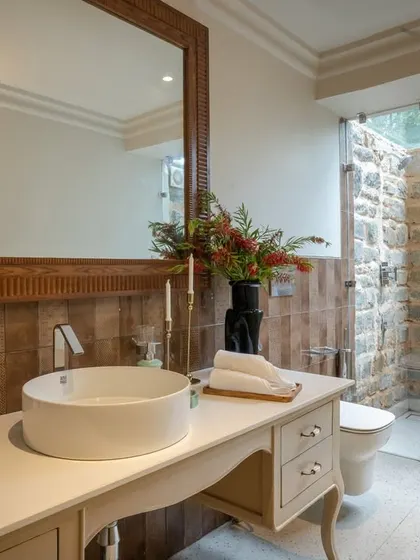 A beautifully balanced bathroom design, where the rustic charm of the local stone shower wall is paired with a clean, white vanity and contemporary vessel sink. It's a perfect blend of modern comfort and natural materials.