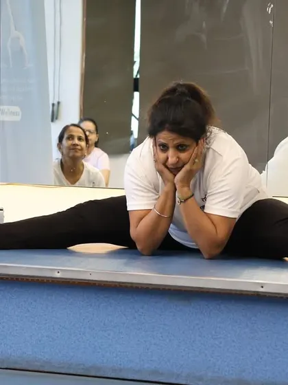 A lighthearted moment during a flexibility session. Even challenging poses can be approached with a smile.