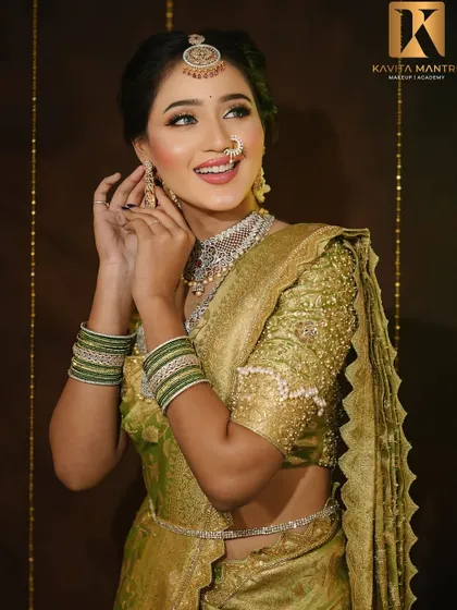 A playful and elegant pose. The makeup is designed to look good from all angles, with a focus on a balanced and harmonious look that complements the green and gold saree.