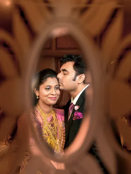 A creative shot through a patterned glass pane, capturing an intimate moment between the couple.