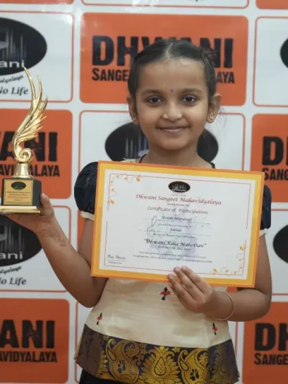 A young student in traditional attire holds her award.