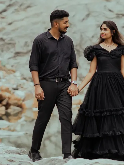 A couple walks hand-in-hand along the rocks by a quarry lake, dressed in elegant black. A beautiful, classic shot in a dramatic location.