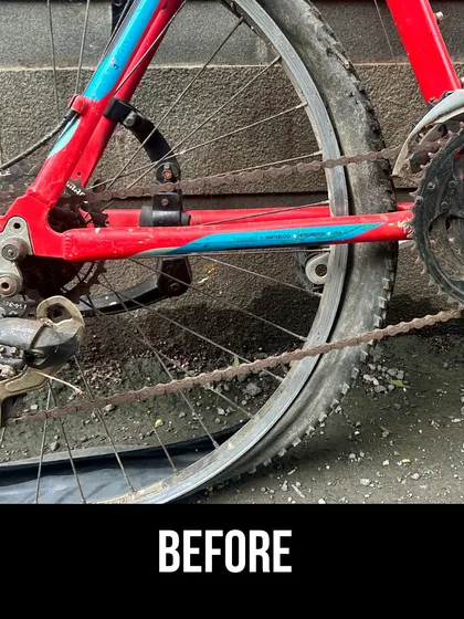 A detailed 'before' shot of the red Trek's rear wheel, showing a broken chain and rusty components. We fix major issues like this as part of our repair service.