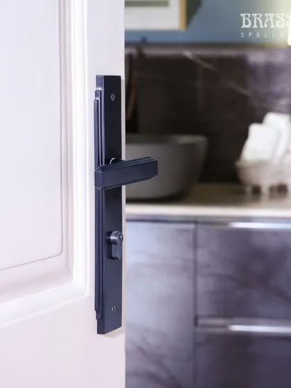 The Natali lever handle on a door leading to the kitchen. The bold, black hardware acts as a unifying design element throughout the different spaces of the home.