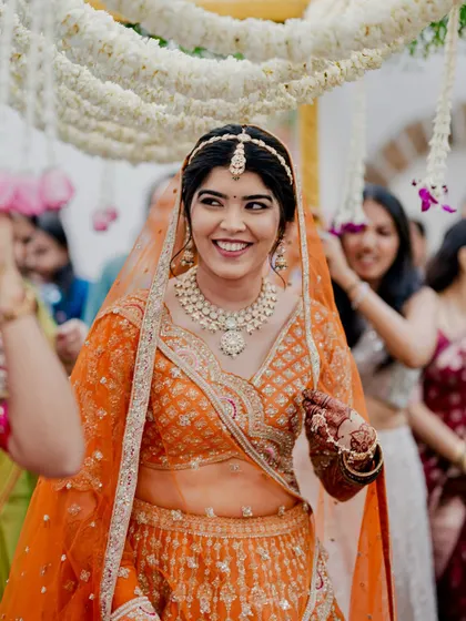 Reeya's joyful entrance. Her smile lights up the frame, and her makeup enhances her happiness, making her look every bit the radiant bride.