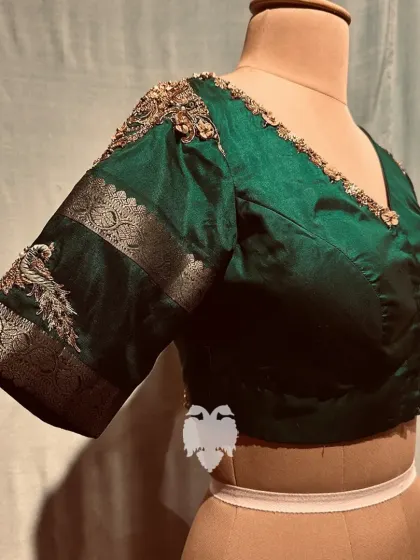 A close-up of the peacock motif on the bottle green blouse.