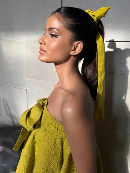 The profile view shows off the clean lines of the winged eyeliner and the beautiful, natural-looking skin texture. This is a perfect example of modern, chic makeup for a fashion feature.
